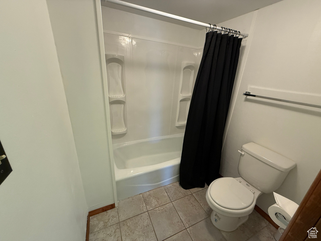 Bathroom featuring toilet and shower / tub combo with curtain