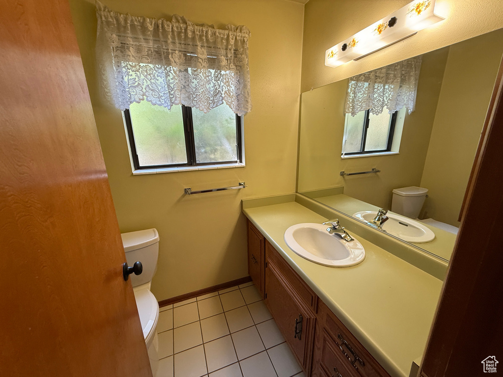 Half bathroom featuring toilet, tile patterned flooring, and vanity