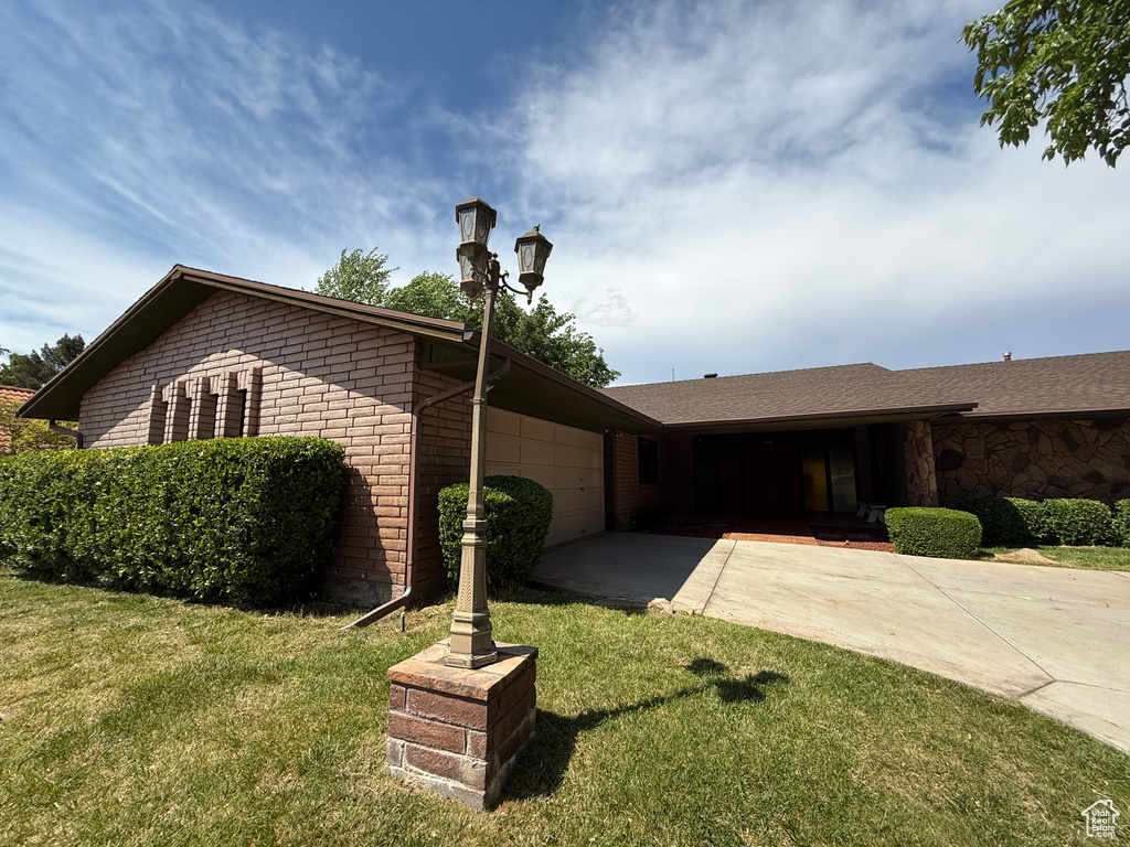 Single story home with driveway, a front yard, a garage, and stone siding