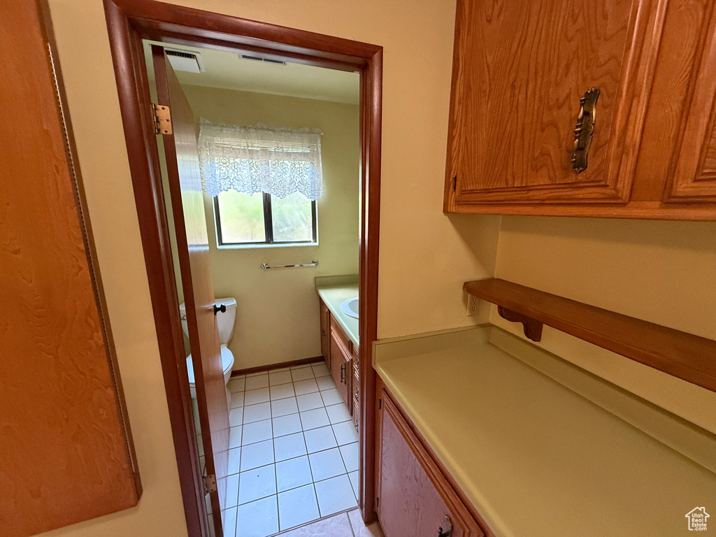 Bathroom with toilet, tile patterned flooring, and vanity