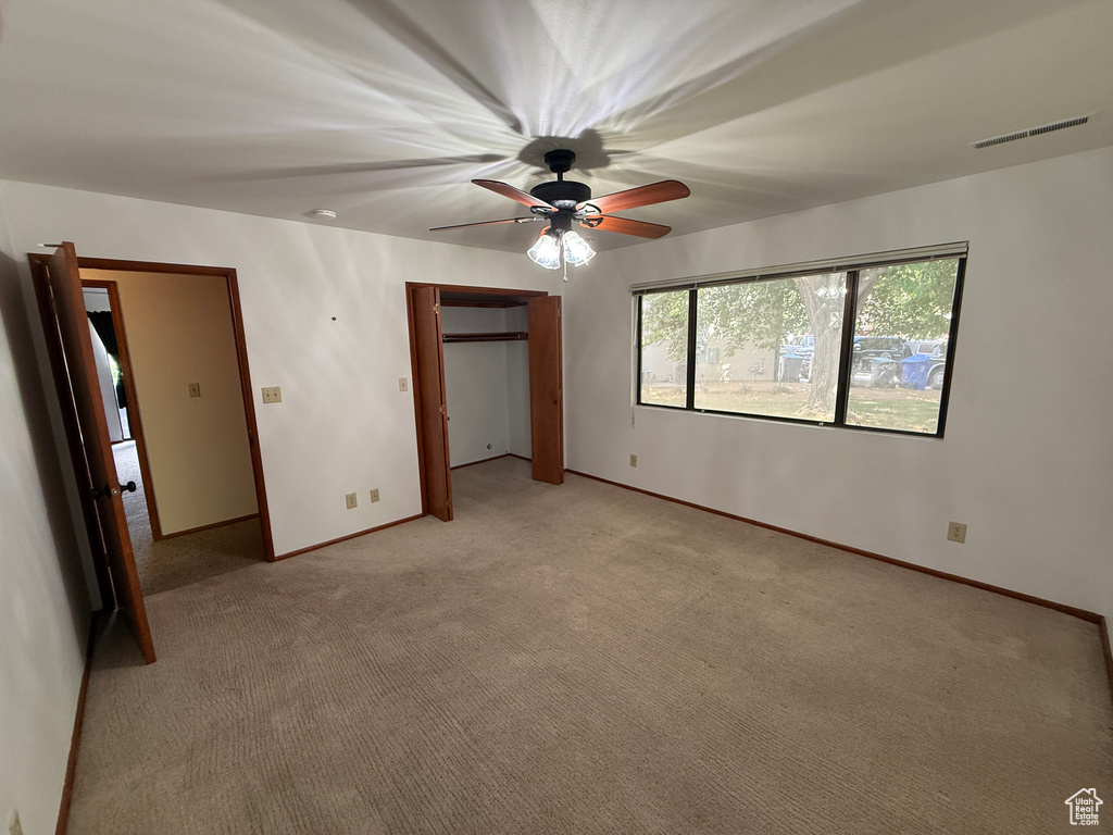 Unfurnished bedroom featuring light colored carpet, baseboards, a ceiling fan, and a closet