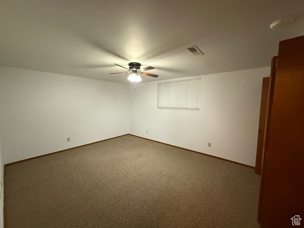 Spare room featuring a ceiling fan, dark carpet, and baseboards