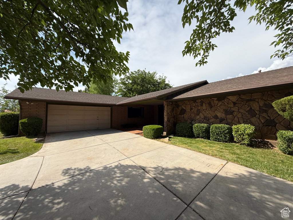Ranch-style house with a garage, driveway, brick siding, and a shingled roof