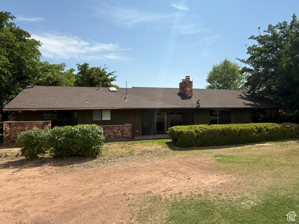 Rear view of house featuring a chimney, a yard, and roof with shingles