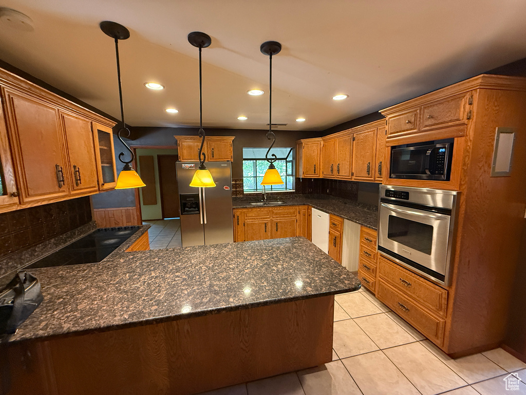 Kitchen featuring stainless steel appliances, a sink, decorative backsplash, decorative light fixtures, and light tile patterned floors