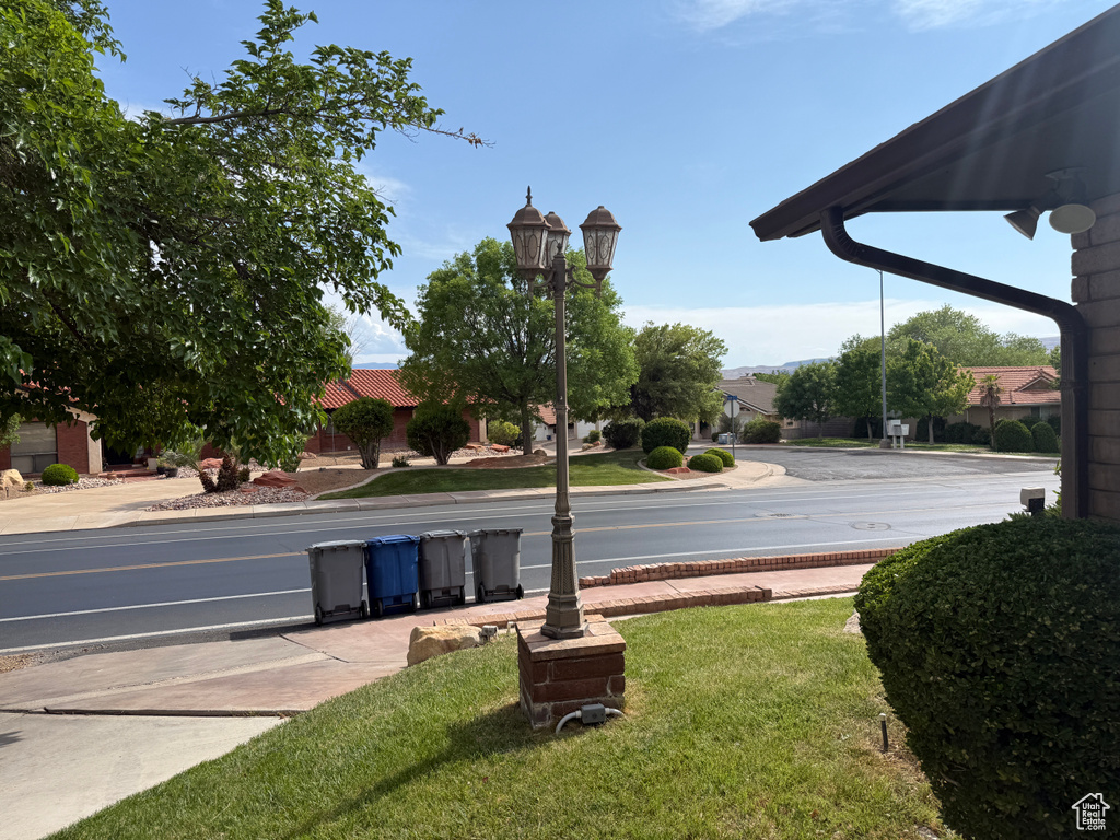 View of asphalt road featuring street lights, sidewalks, and curbs