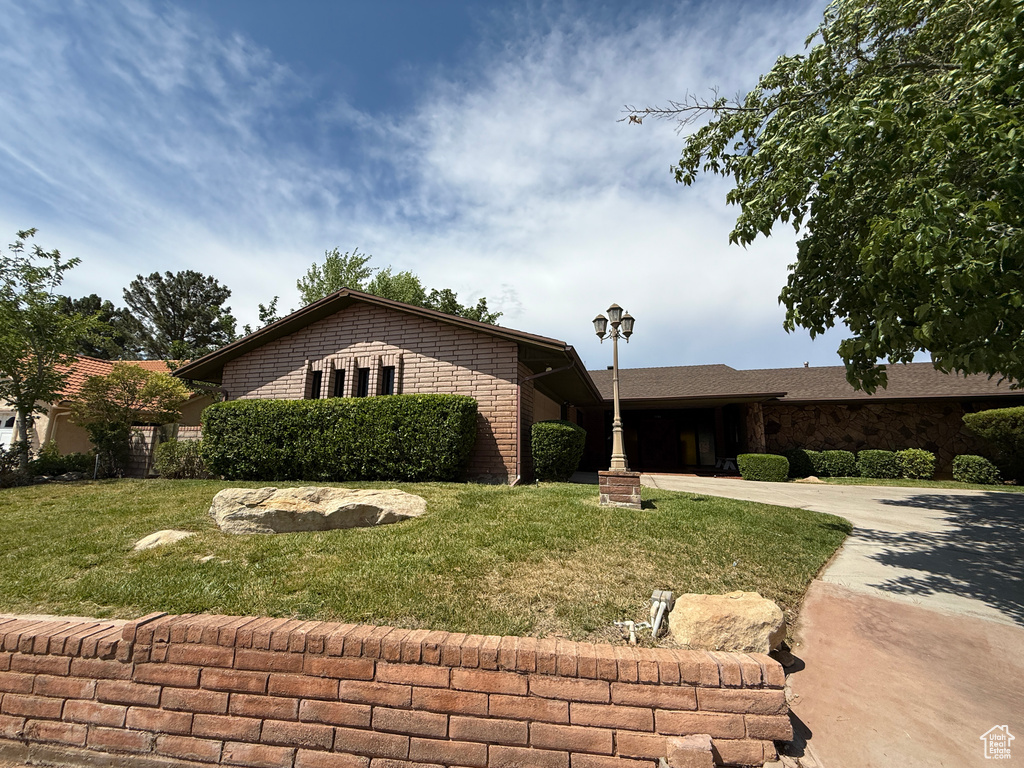 Single story home featuring concrete driveway, a front lawn, and brick siding