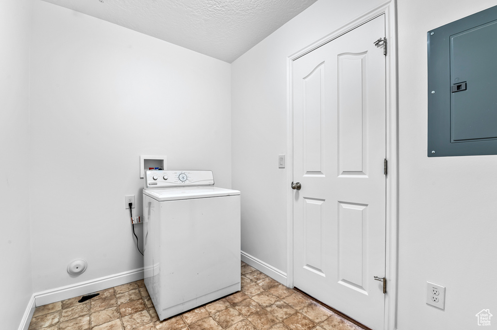 Laundry room with washer / clothes dryer, electric panel, baseboards, stone finish floors, and a textured ceiling