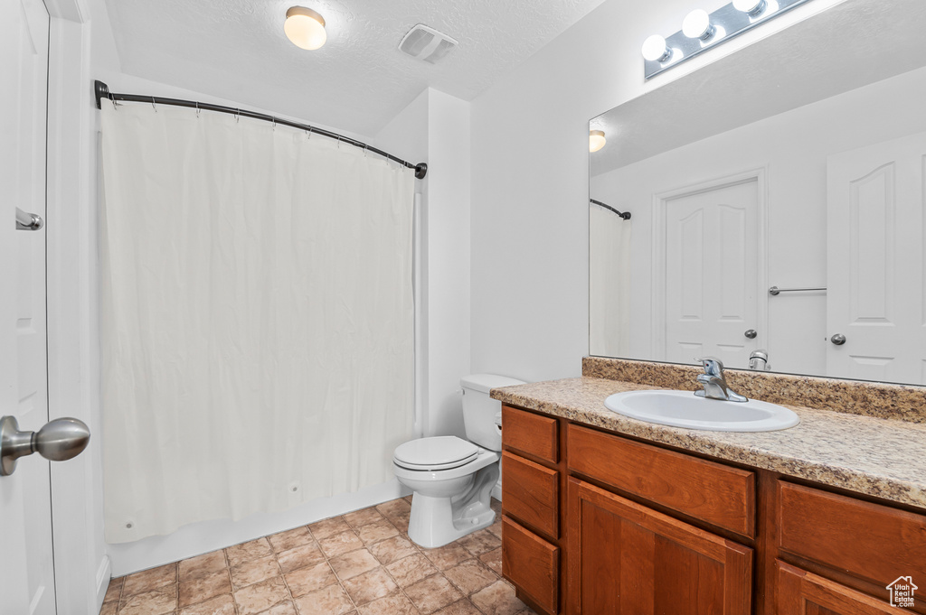 Full bathroom with vanity, toilet, a textured ceiling, and shower / tub combo
