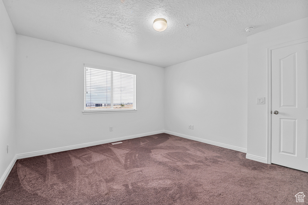 Unfurnished room with dark colored carpet, a textured ceiling, baseboards, and a smoke detector