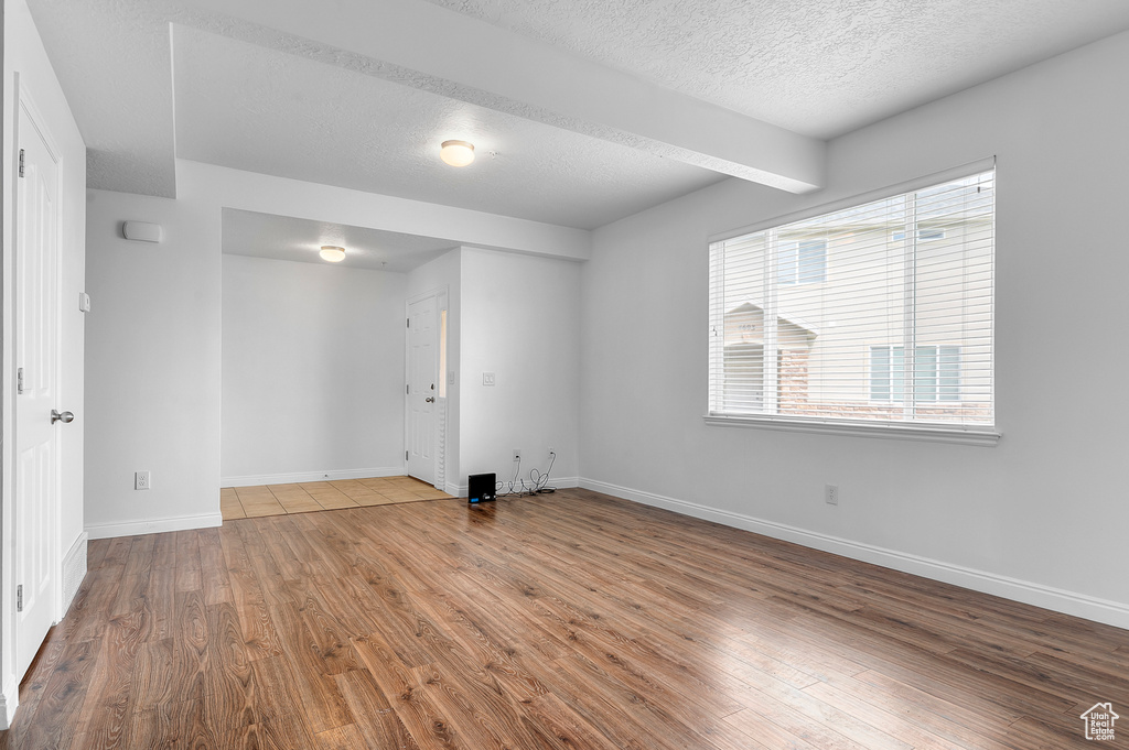 Unfurnished room with wood finished floors, a textured ceiling, and baseboards