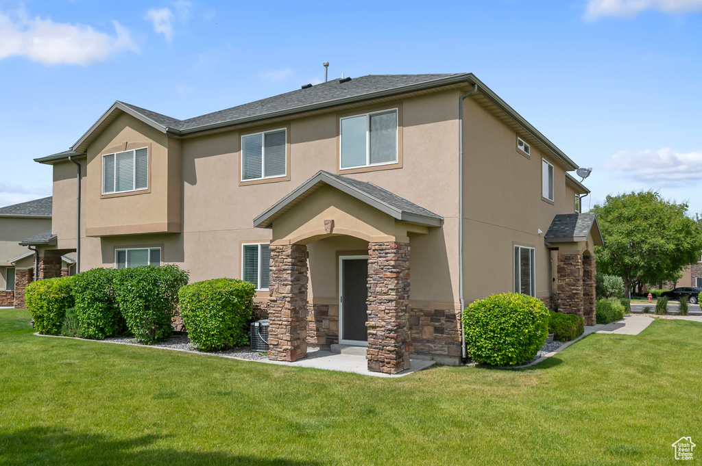 View of front of house featuring stucco siding, stone siding, and a front yard