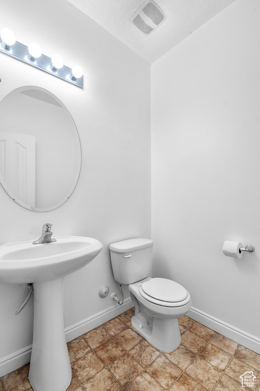 Bathroom featuring toilet, baseboards, and a sink