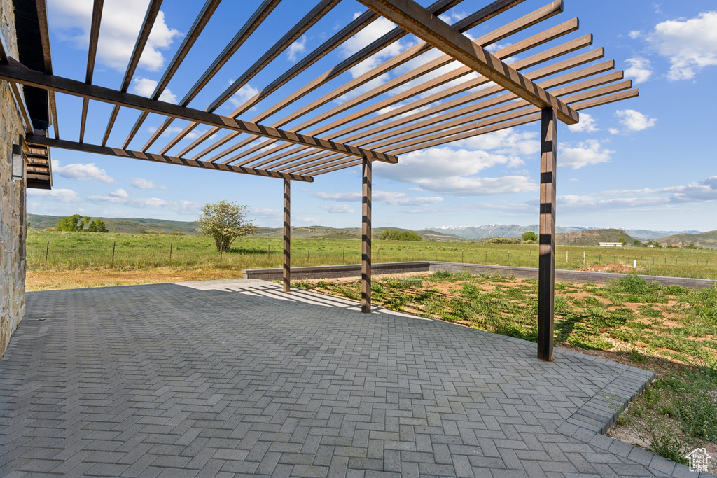 View of patio featuring a view of countryside, a pergola, and a mountain view