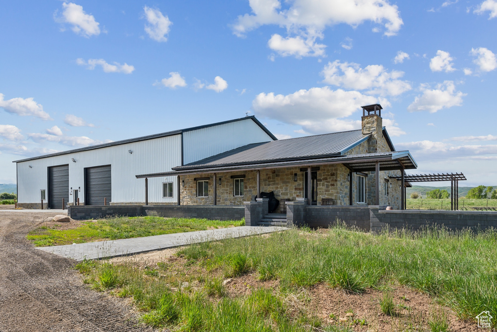 View of front of home featuring stone siding, driveway, metal roof, and covered porch