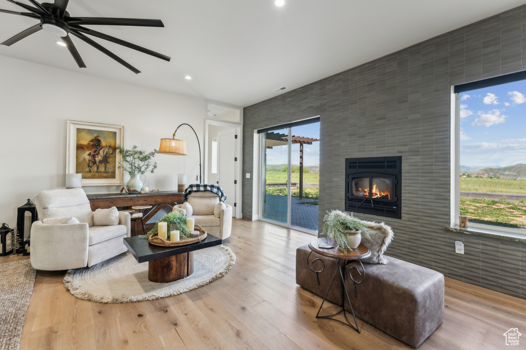 Living area with a fireplace, a ceiling fan, wood finished floors, recessed lighting, and an accent wall