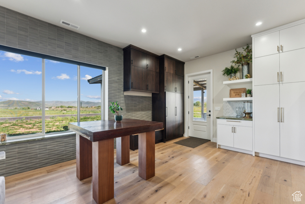 Kitchen with light wood-style floors, decorative backsplash, open shelves, recessed lighting, and white cabinets