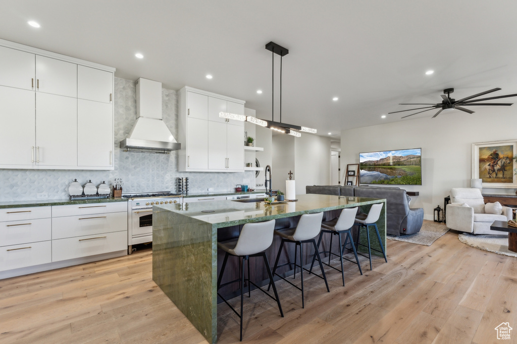 Kitchen with custom range hood, high end range, a sink, a kitchen bar, and open shelves