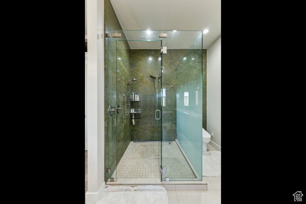 Bathroom featuring tile patterned flooring, toilet, a stall shower, and baseboards