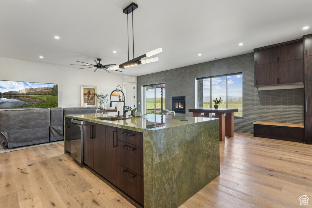 Kitchen featuring open floor plan, a sink, dark brown cabinetry, recessed lighting, and a ceiling fan