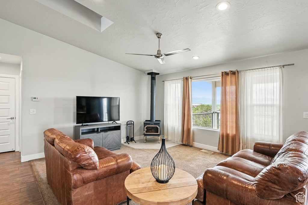 Living area with baseboards, a wood stove, ceiling fan, recessed lighting, and light wood-type flooring
