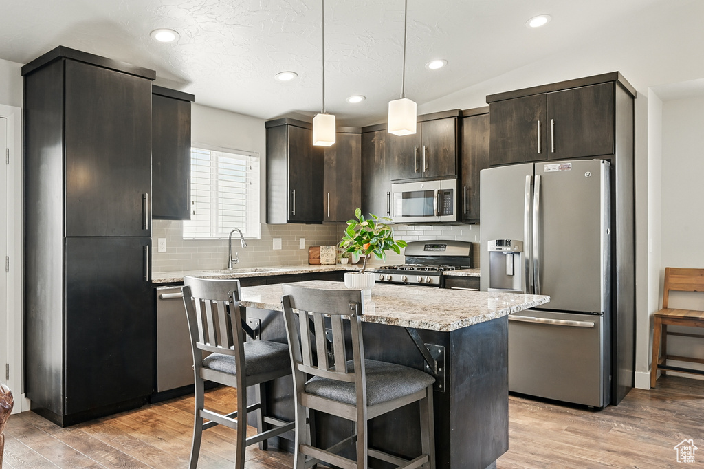 Kitchen with stainless steel appliances, a sink, backsplash, a center island, and a breakfast bar