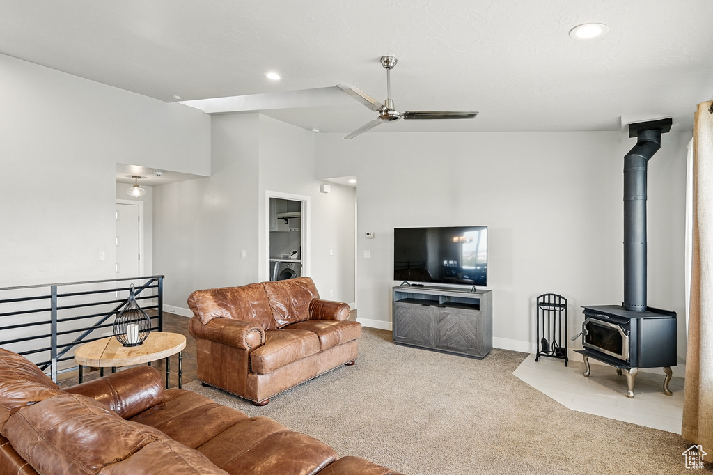 Living room featuring a wood stove, carpet flooring, baseboards, recessed lighting, and a ceiling fan