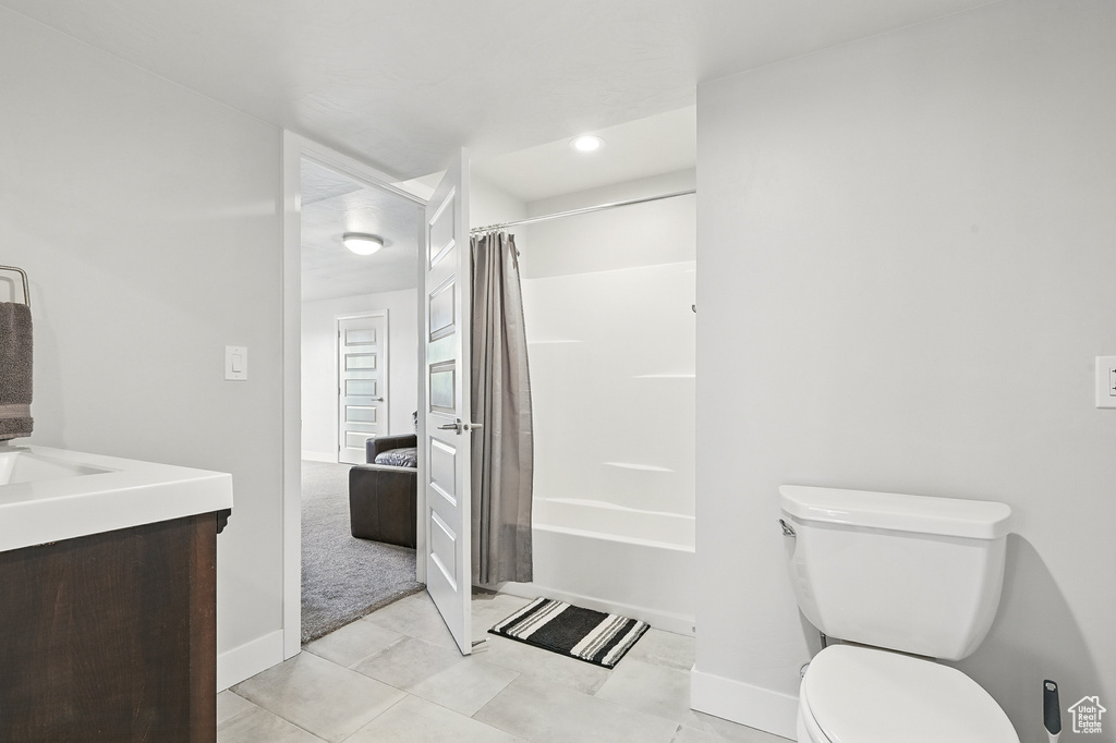Full bathroom with toilet, shower / tub combo, vanity, baseboards, and tile patterned floors