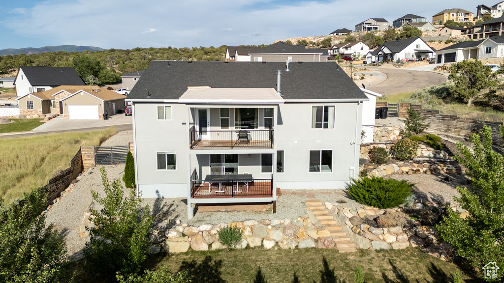 Rear view of house featuring a balcony, a residential view, stucco siding, and a wooden deck