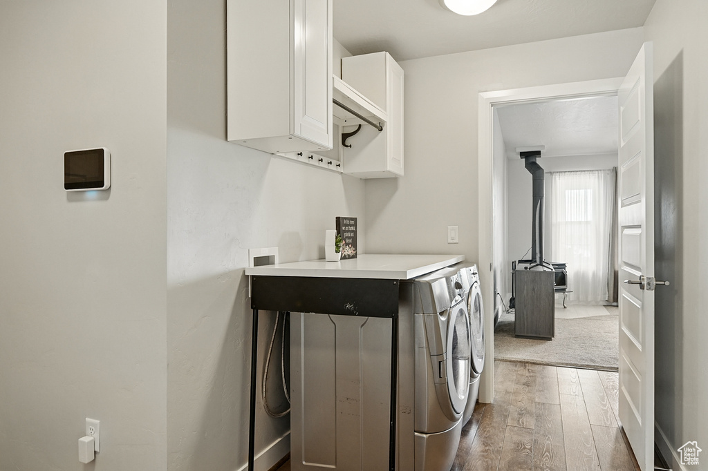 Laundry room with cabinet space, hardwood / wood-style flooring, and separate washer and dryer