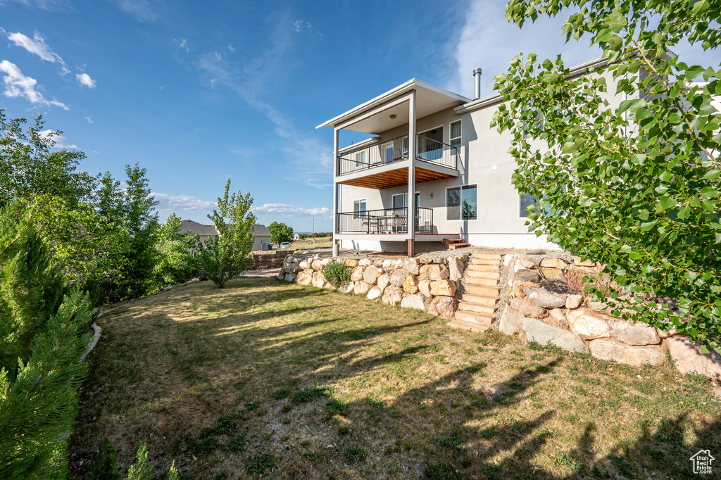 Rear view of property with a balcony and a lawn