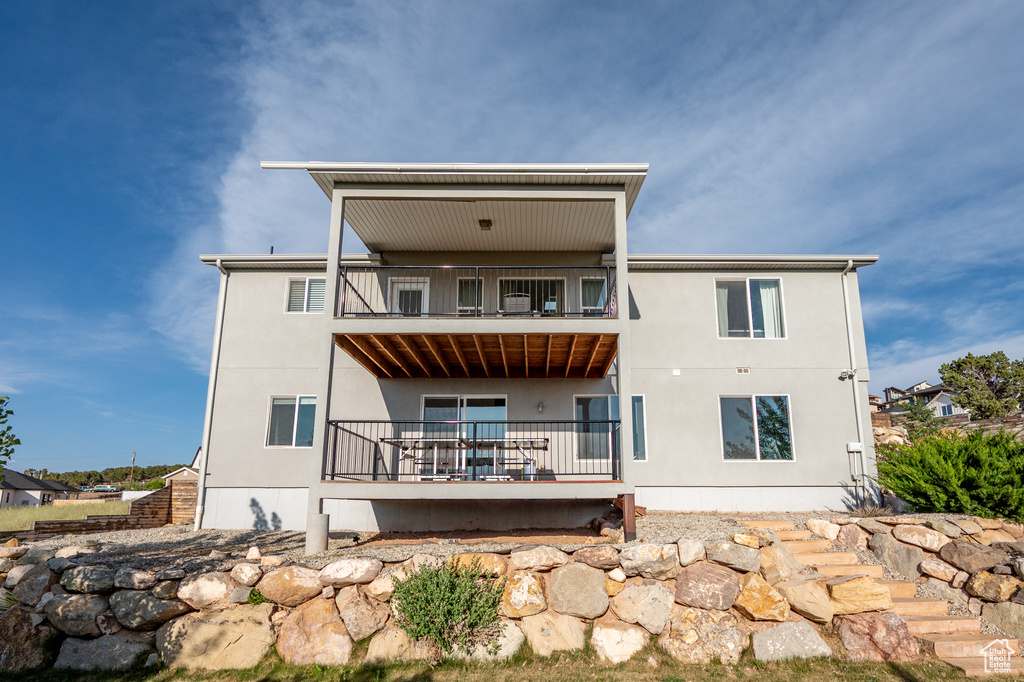 Back of house featuring a balcony and stucco siding