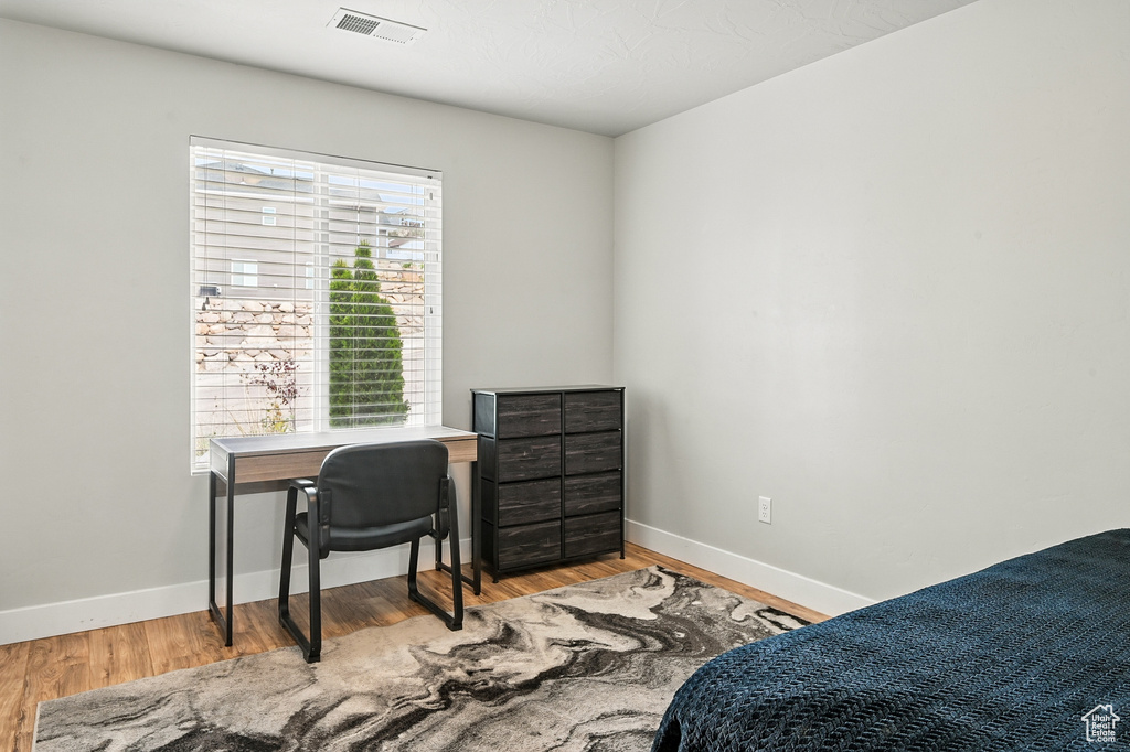 Bedroom with wood finished floors, baseboards, and a desk