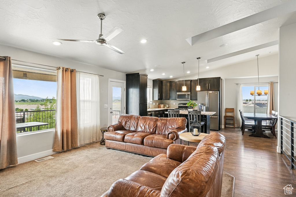 Living area featuring vaulted ceiling, plenty of natural light, recessed lighting, a ceiling fan, and dark wood-style flooring