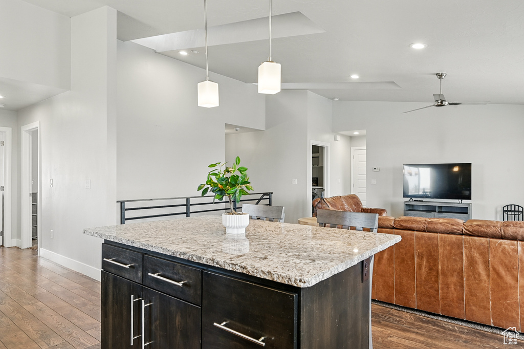 Kitchen with dark wood finished floors, baseboards, recessed lighting, open floor plan, and hanging light fixtures