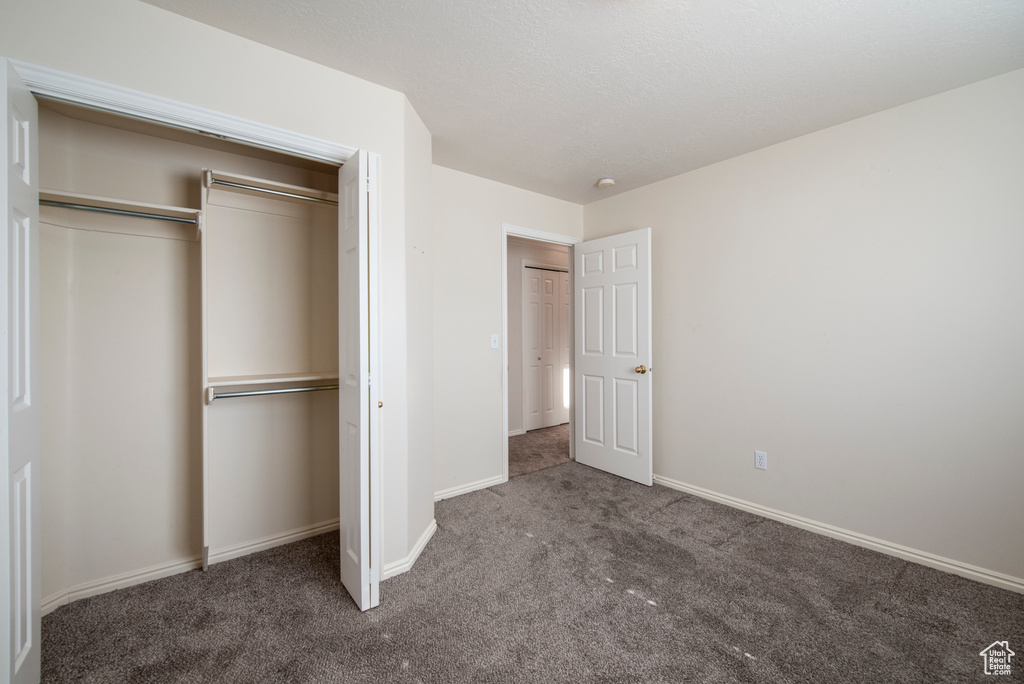 Unfurnished bedroom featuring carpet flooring, baseboards, and a closet