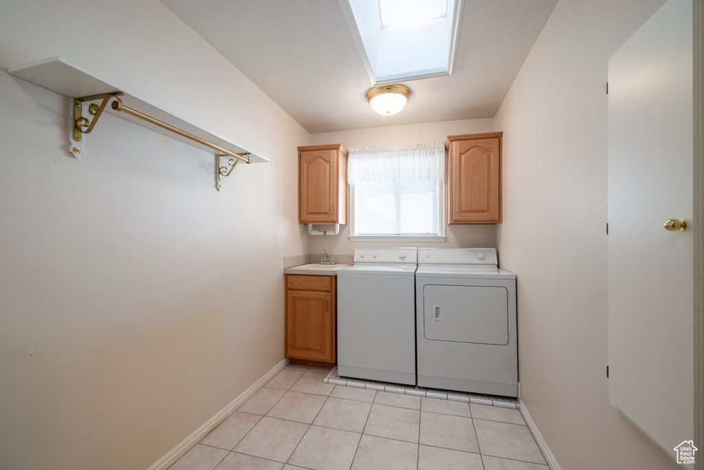 Laundry room featuring independent washer and dryer, baseboards, cabinet space, light tile patterned floors, and a skylight
