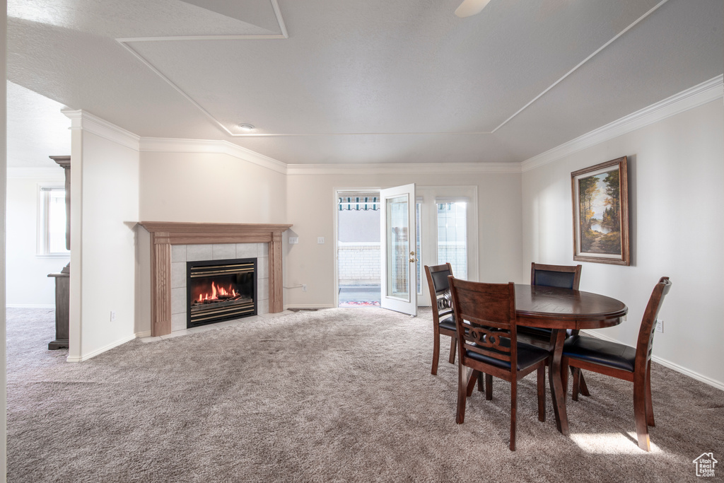 Dining room featuring carpet floors, a tile fireplace, ornamental molding, and baseboards