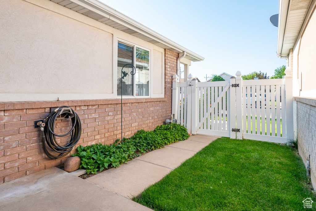 View of side of home with a gate, brick siding, and stucco siding