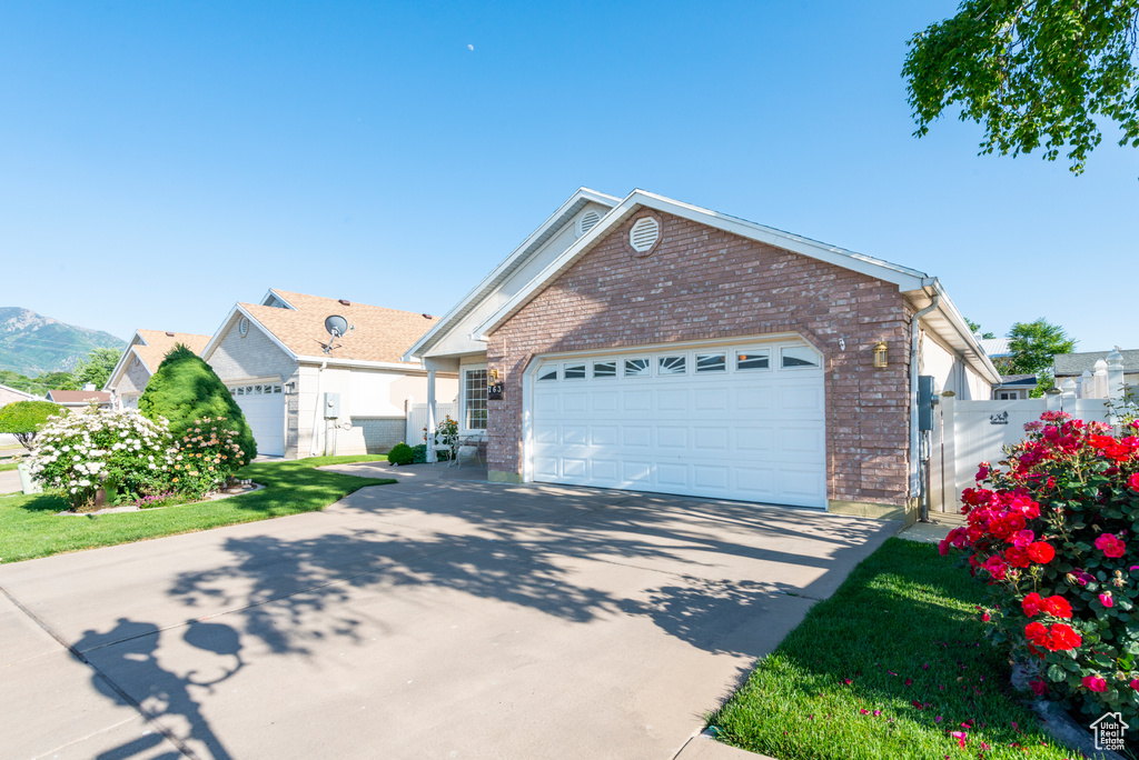 Single story home with brick siding, driveway, a gate, and a garage