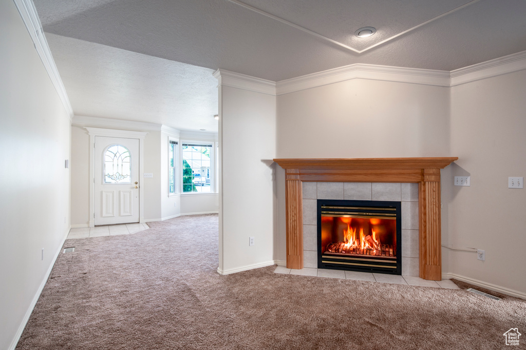 Carpeted foyer featuring a fireplace, ornamental molding, and baseboards
