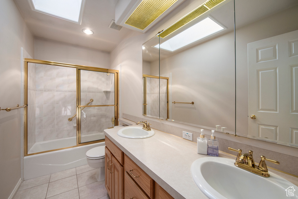 Bathroom with double vanity, toilet, shower / bath combination with glass door, tile patterned floors, and recessed lighting