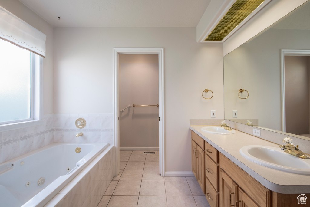 Full bath with double vanity, a whirlpool tub, tile patterned floors, and baseboards