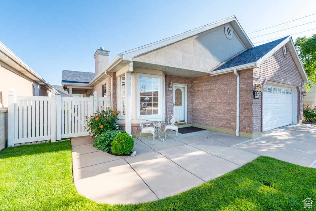 View of front of property with a garage, brick siding, a chimney, and concrete driveway