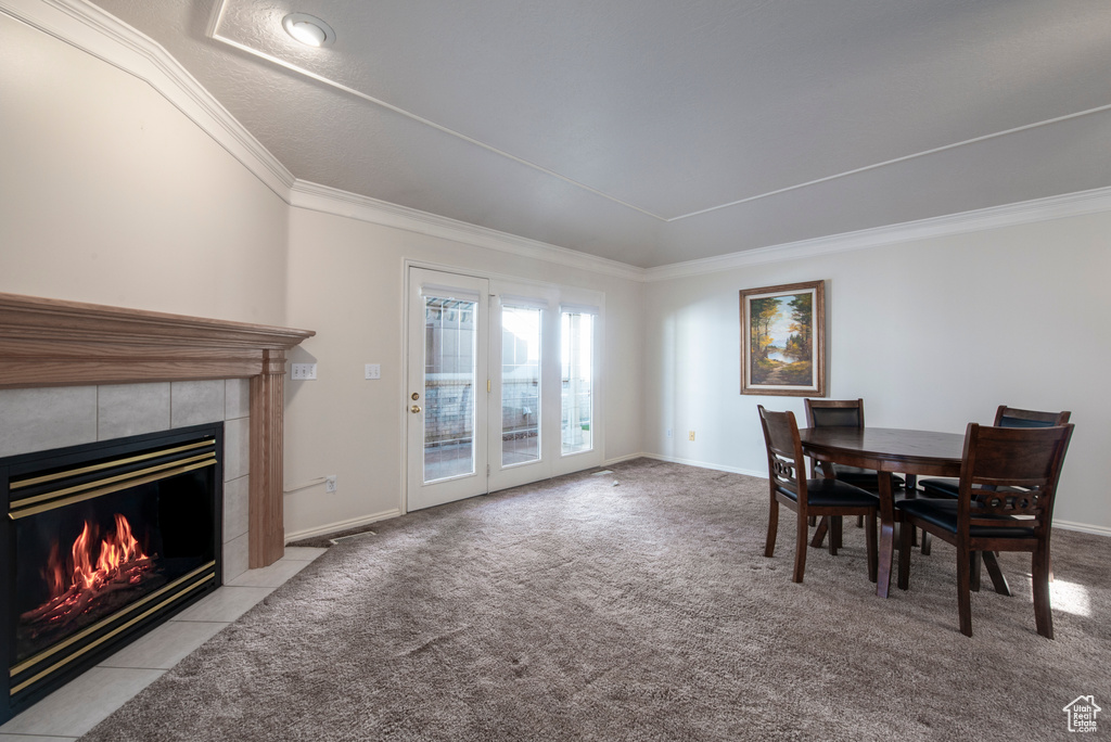 Carpeted dining space with a fireplace, crown molding, and baseboards