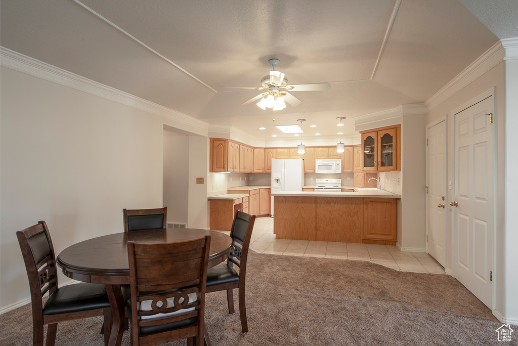 Dining room with light colored carpet, a raised ceiling, a ceiling fan, crown molding, and light tile patterned flooring