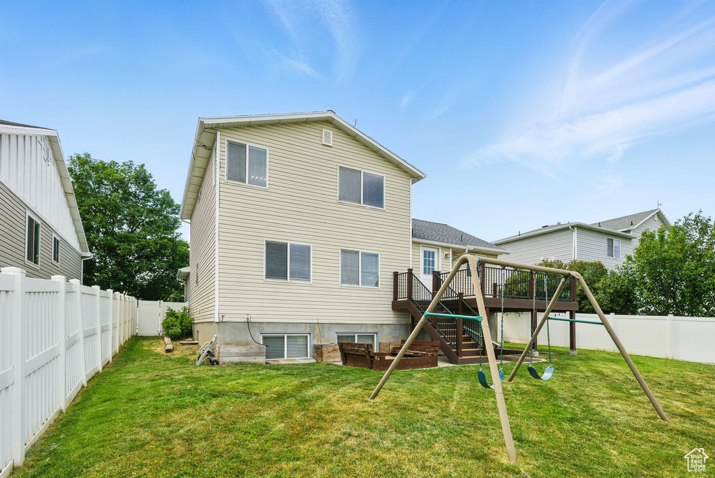 Back of property featuring stairway, a wooden deck, and a playground