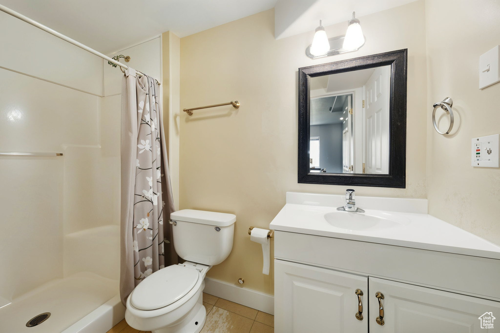 Full bath with tile patterned floors, toilet, vanity, and curtained shower