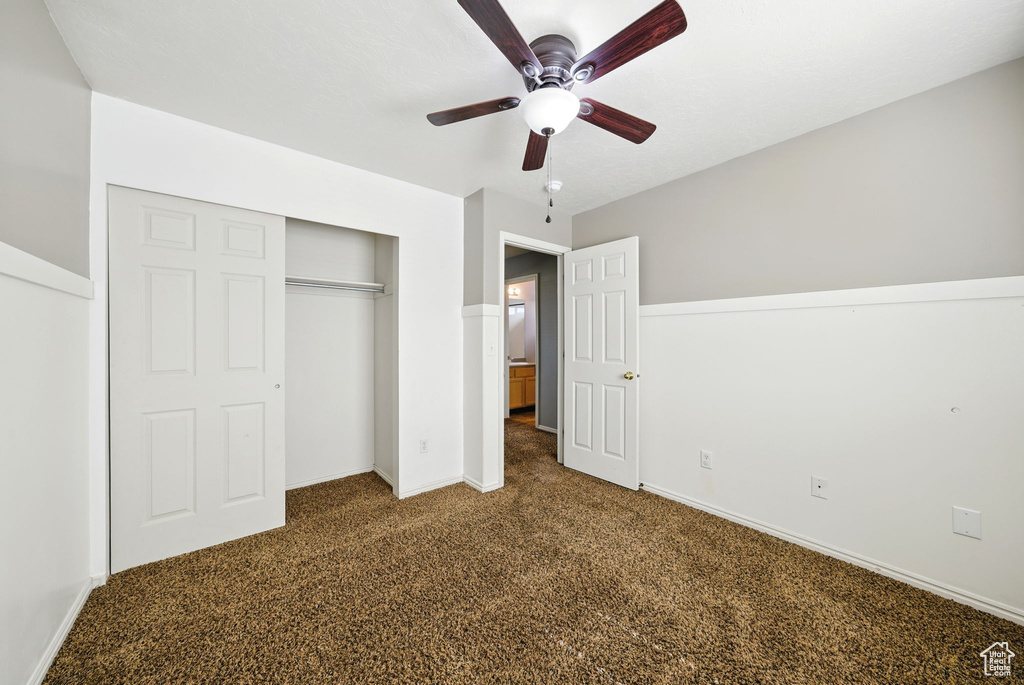 Unfurnished bedroom with carpet flooring, a closet, baseboards, and a ceiling fan