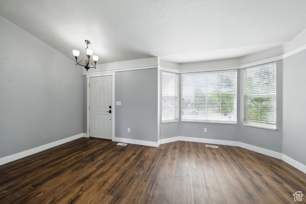 Entrance foyer featuring a chandelier, dark wood-type flooring, and baseboards